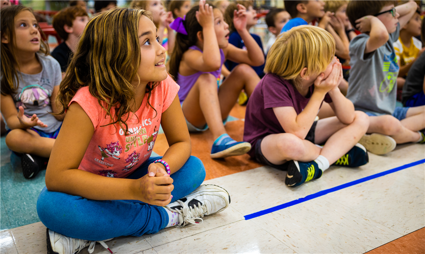 Students sit on the floor of the cafeteria
